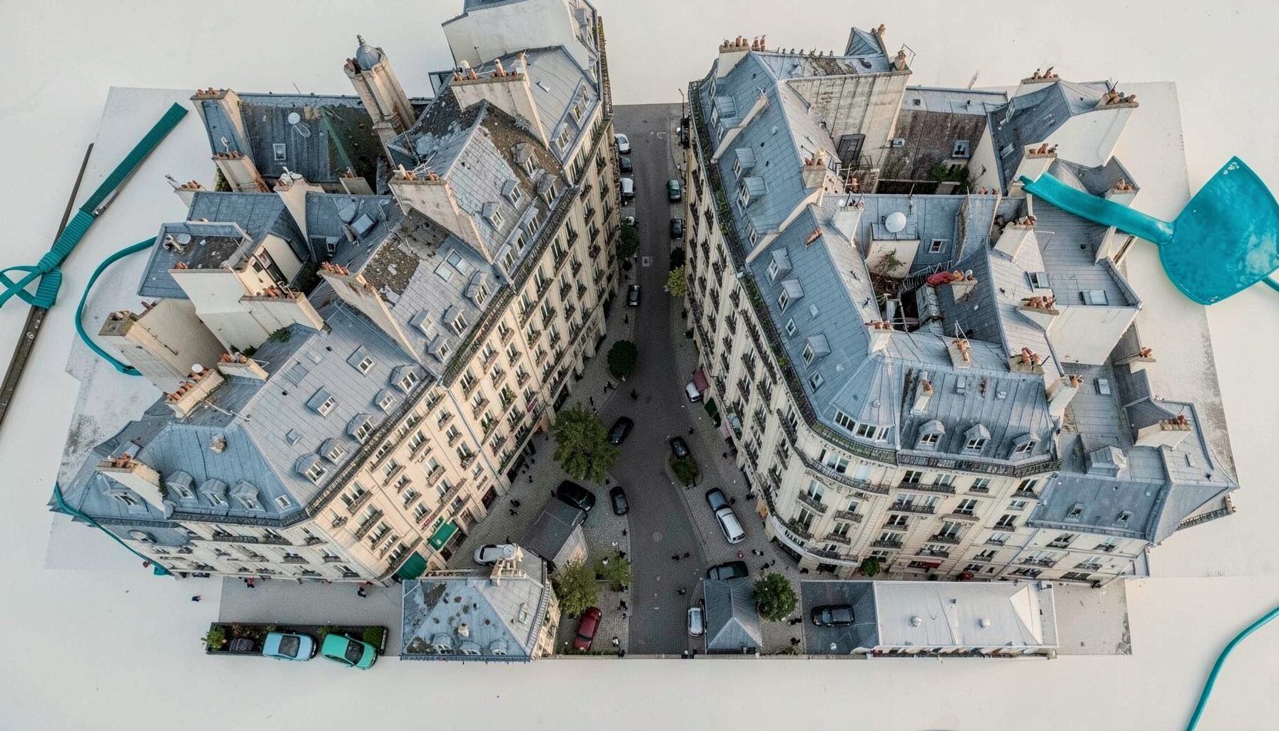 Vue aérienne du quartier Mouffetard avec ses toits parisiens et la rue pavée serpentant entre les immeubles haussmanniens, sous une lumière douce de fin d'après-midi